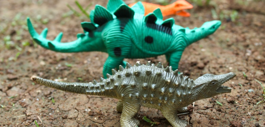 Children's plastic dinosaur toys in a garden. 