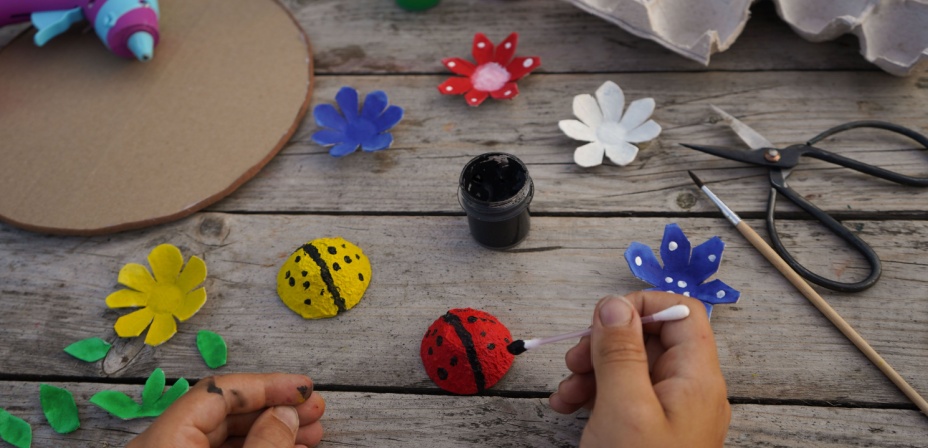 A childe painting egg carton pieces into bugs for fun spring activity for kids. 