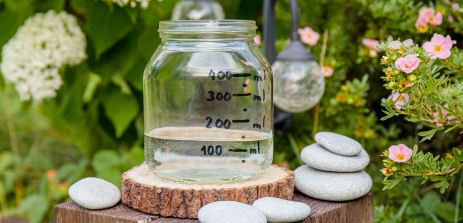 A jar of water with measurements written on it collecting rain water for a fun spring activity. 